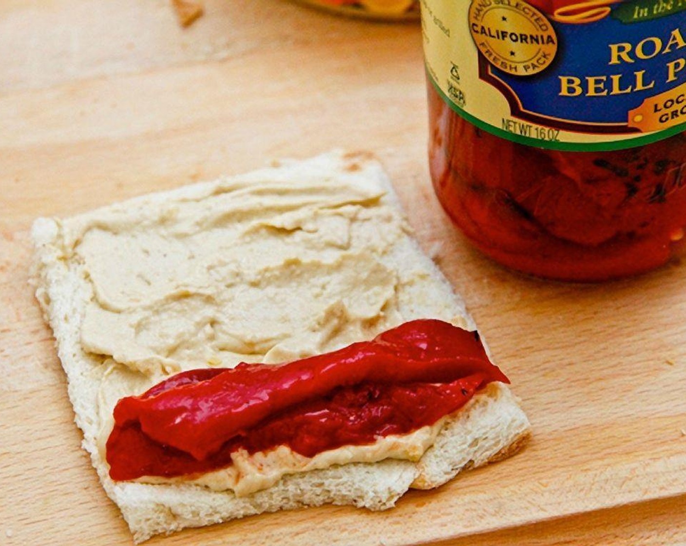 step 3 For the first combination, spread the Hummus (2 Tbsp) onto a slice of bread, then align the Fire Roasted Red Peppers (200 g) all in one row, and only at the bottom.