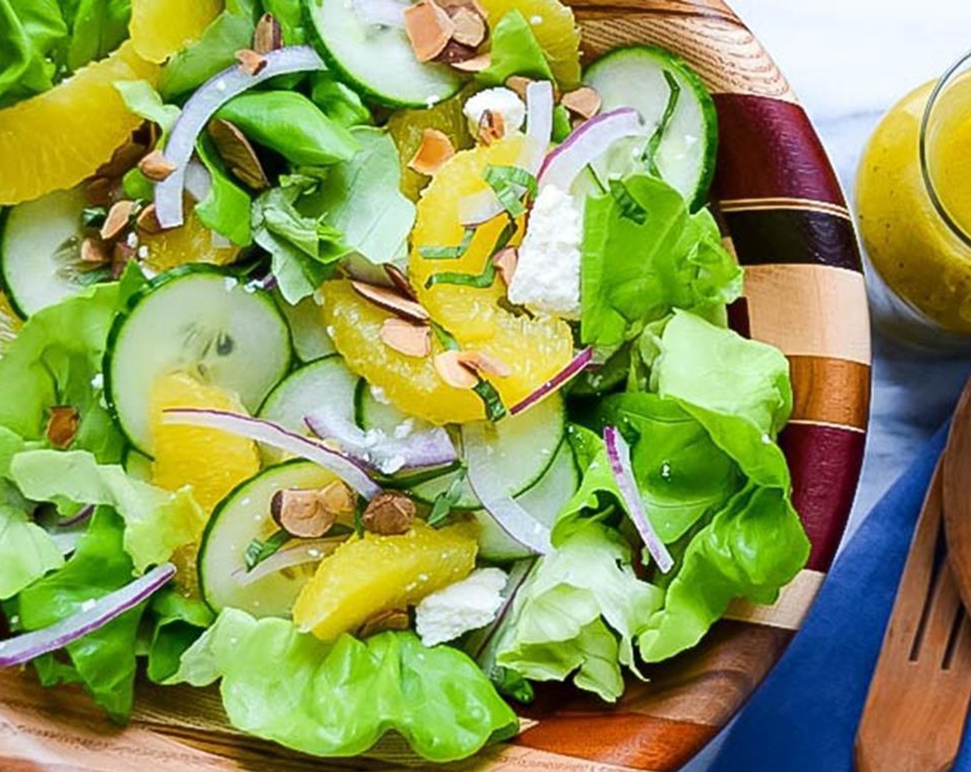 step 3 Add the Bibb Lettuce (1 head) to a large salad bowl. Top with Red Onion (1/3 cup), Queso Fresco (3/4 cup), Cucumber (1/2), and orange segments. Add 4-5 tablespoons of dressing and toss the salad. If it needs more dressing, add more a little at a time. Sprinkle the salad with the Toasted Sliced Almonds (4 Tbsp) and Fresh Basil (3). Serve.