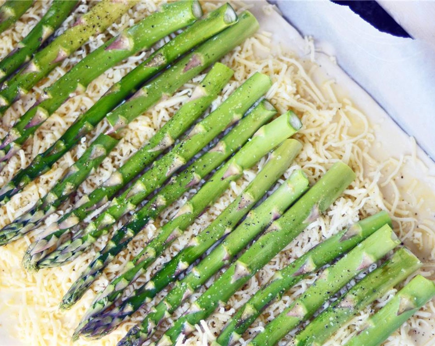 step 7 Evenly spread Gruyère Cheese (2 cups) over puff pastry. Gently press asparagus spears into cheese. Brush with Olive Oil (1 Tbsp) and season with Salt (to taste) and Ground Black Pepper (to taste).