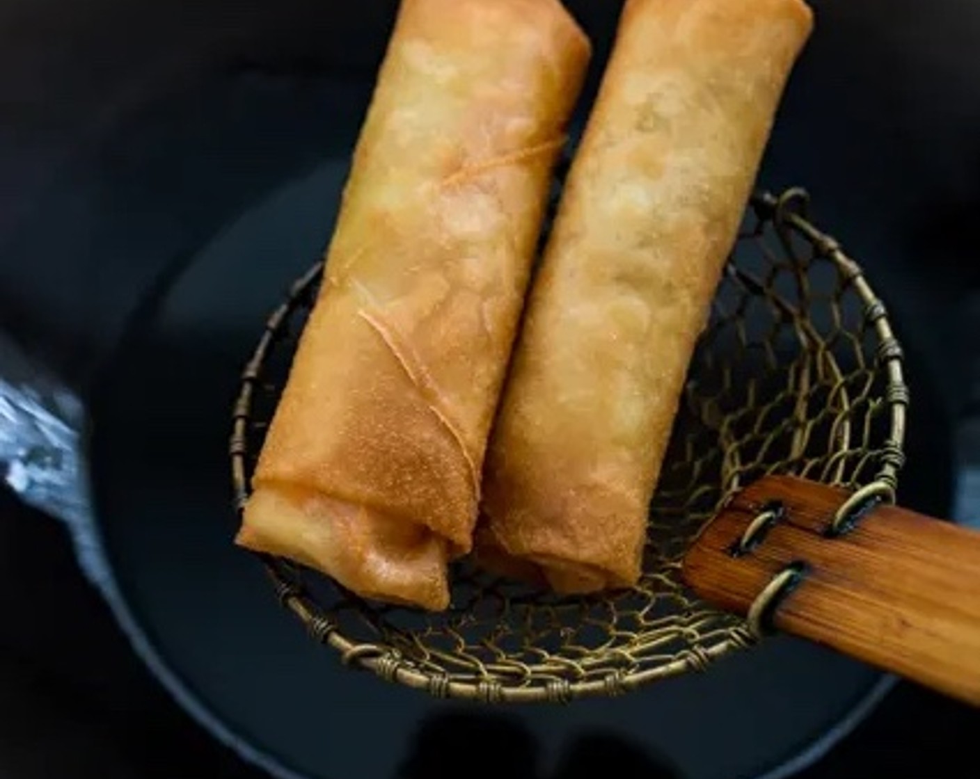 step 7 Remove the spring rolls from the wok with a spider skimmer and place them on a baking sheet lined with paper towels or oil-absorbing paper.