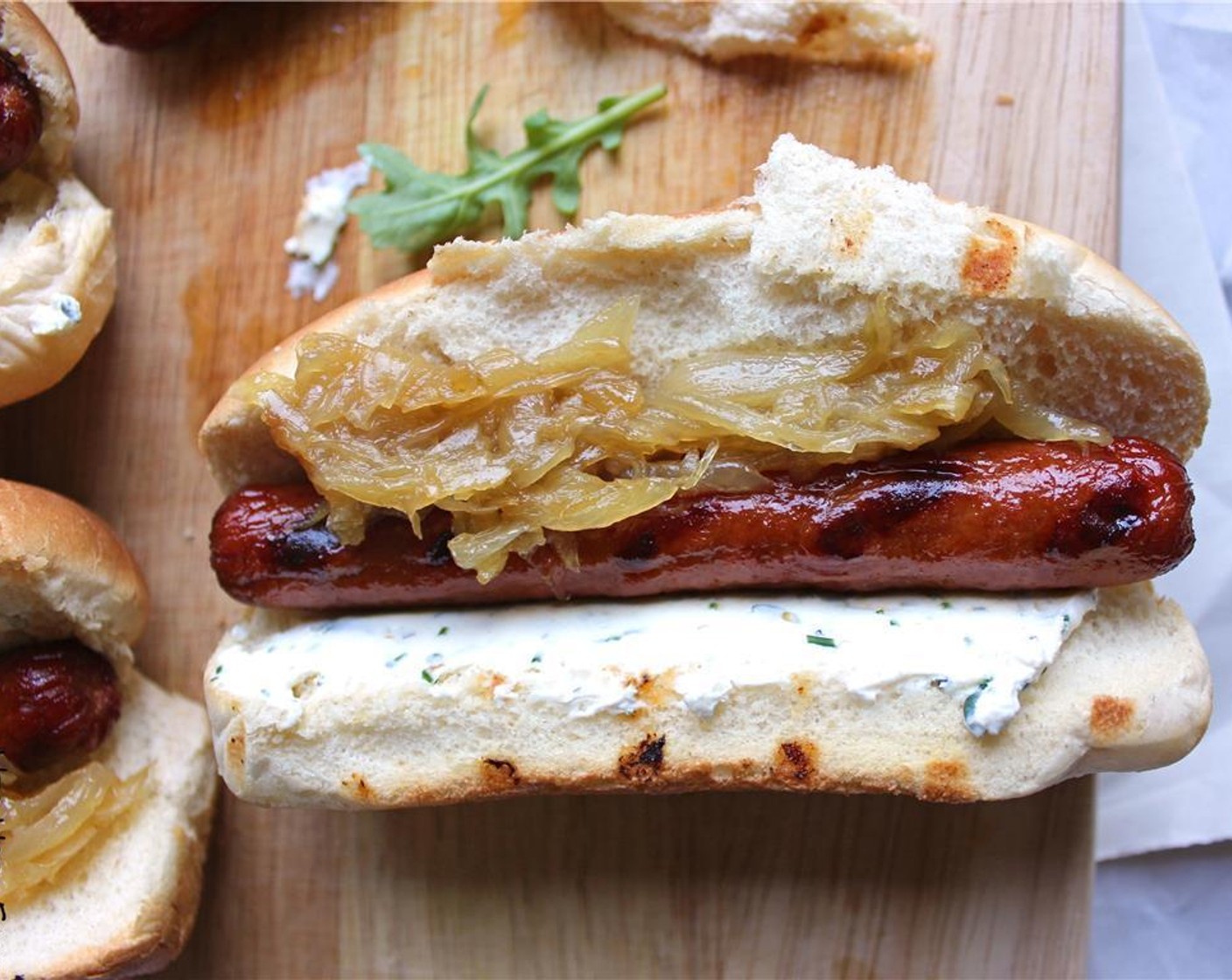 step 6 Assemble your hot dog by putting herbed cream cheese on one side of the bun, caramelized onions on the other, your beer braised hot dog in the middle and Arugula (to taste) on top, if you like.