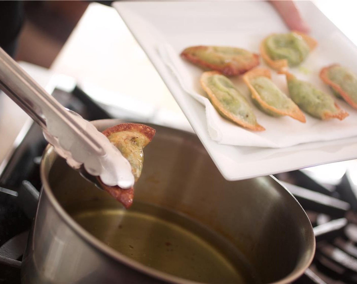 step 16 Carefully fry the wontons for 3 minutes on each side until golden and crispy. Place the fried wontons on a paper towel to drain the oil.