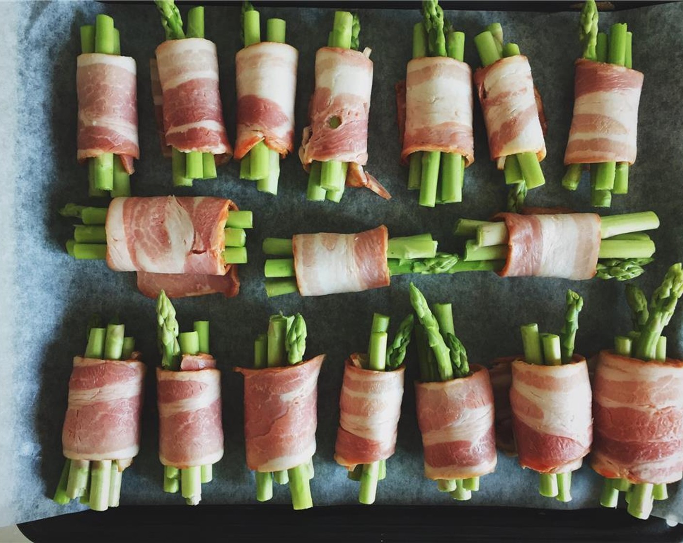 step 8 Roll up all the bacon slices with asparagus or cheese if you like. Line them up on a baking tray with parchment paper. Sprinkle with Salt (to taste) and Ground Black Pepper (to taste). Drizzle with Olive Oil (as needed).